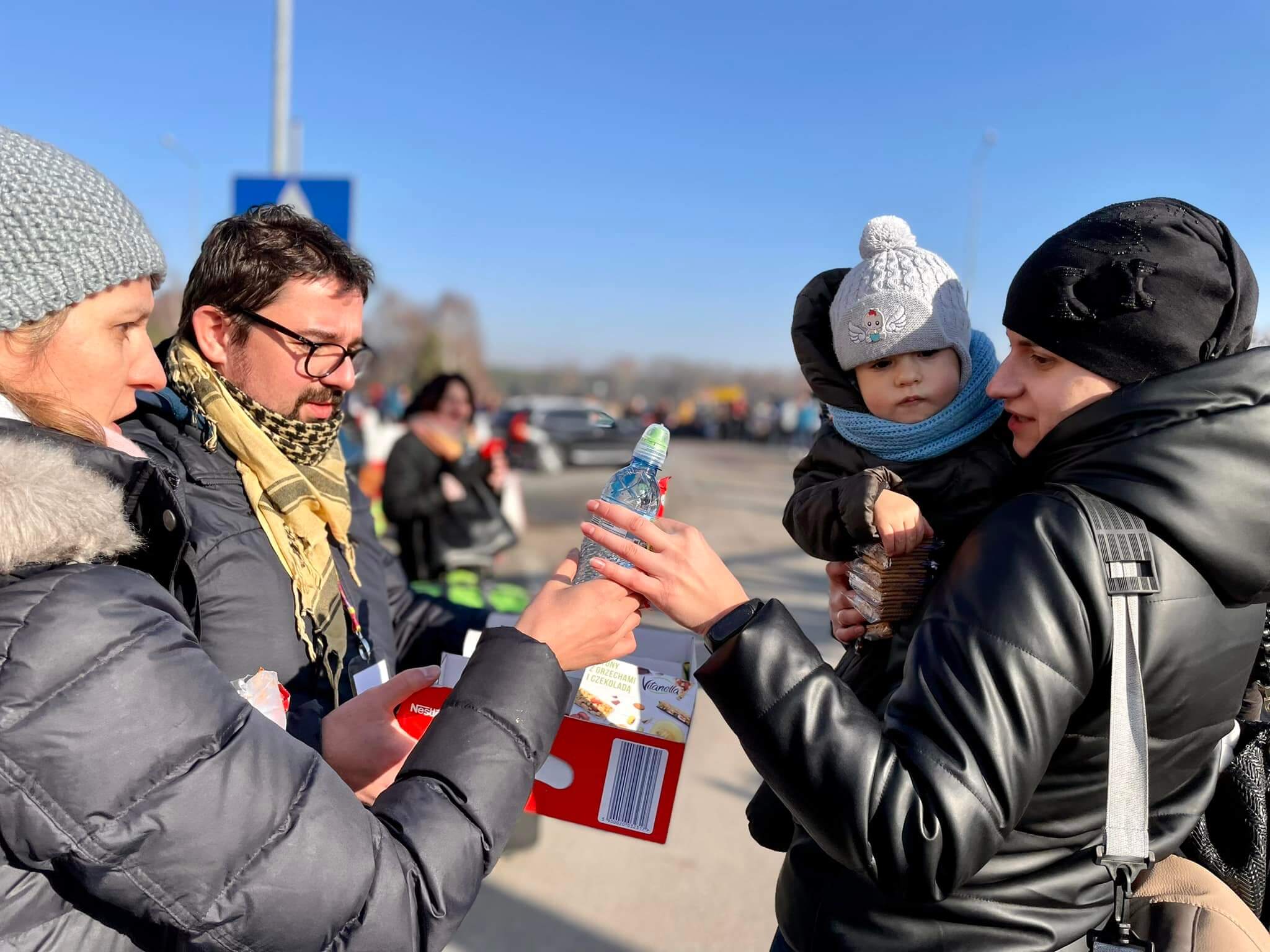 Mateusz Gasiński, Ola Hera i Anna Kieniewicz z fundacji Dobra Fabryka przekazują gorącą herbatę, koce i kanapki przy przejściu granicznym Korczowa-Krakowiec